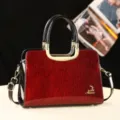 Détail de sac à main en cuir verni rouge, élégant sac bandoulière avec détails dorés. - Rouge