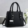 Vista detallada del bolso de mujer en cuero sintético negro con asas dobles y mini colgante. - Negro