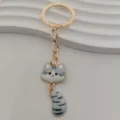 Detailed view of a cute tabby cat keychain featuring a gold metal ring and enamel pendant. - White and Gray Striped Cat Style (6)