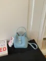 Light blue litchi grain bucket bag, stylish commuter handbag with metal lock and shoulder strap. - With Charm / Blue
