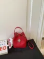 Red leather bucket bag stylish commuter handbag with metal lock and shoulder strap variant - With Charm / Red