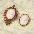 Vintage cameo brooch set detail showcasing intricate antique filigree and resin portraits. - Gold-Pink White