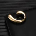Detailed closeup of a luxurious gold alloy fashion brooch with modern abstract curved design. - Streamlined Abstract Shape (X1178)
