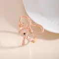 Primo piano di elegante portatovagliolo a fiocco oro rosa, finitura metallica per tavola. - Fiocco (X1132-9)