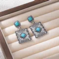 Detailed shot of retro silver bohemian turquoise drop earrings with geometric patterns. - Blue