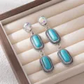 Detailed close-up of Bohemian retro turquoise drop earrings with vintage silver frames. - Blue