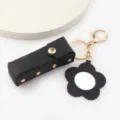 Étui à rouge à lèvres en cuir noir porte-clés avec un pendentif miroir fleur, doré. - Noir