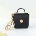 Gros plan détail du porte-clés mini pochette en cuir noir avec accessoires dorés. - Noir