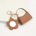Stijlvolle bruine lederen mini tas sleutelhanger met bloem spiegel, creatief cadeau. - Gebogen Tas + Bloemen Spiegel / koffiekleur
