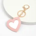 Gros plan détaillé du porte-clés miroir en cuir cœur rose mignon avec des ferrements. - Rose