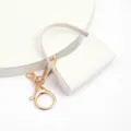 Mini porte-clés sac à main en cuir PU blanc détail avec finitions métalliques dorées et coutures. - Blanc