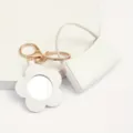 Gros plan detail du porte-cles mini sac miroir fleur en cuir blanc avec pieces d'or. - Sac Courbé + Miroir Fleur / Blanc