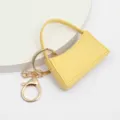Gros plan détail du porte-clés sac à main miniature en cuir PU jaune avec anneau. - Jaune
