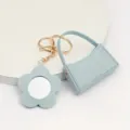 Leuke lichtblauwe lederen mini handtas sleutelhanger met bijpassende bloem spiegel hanger. - Gebogen Tas + Bloemen Spiegel / Blauw