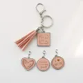 Ensemble porte-clés pompon en cuir rose avec breloques métalliques gravées de lettres maman. - Rose