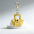 Gele lederen minitas sleutelhanger, schattige macaron handtas charm en gouden mode-accessoire. - Geel