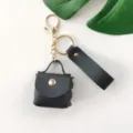 Porte-clés mini sac à main en cuir PU noir avec quincaillerie dorée et lanière chic. - Noir