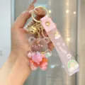 Close-up detail of the clear liquid quicksand bear keychain with cute pink strap and charms. - Pink