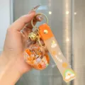 Nahaufnahme des süßen Bubble-Tea-Flüssig-Treibsand-Schlüsselanhängers mit bunten Elementen. - Orange