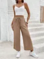 Detailed view of the casual wide-leg trousers paired with white top on stone stairs. - S / Khaki