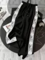 Schwarze Weite Hose mit weißem Spitzen-Seitenstreifen, hoher Bund und sportlicher Stil. - S / Unterteile / Schwarz