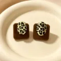 Detalle de pendientes ovalados con estampado de leopardo sobre cojines de terciopelo. - Marrón Flocado Leopardo