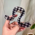 Primo piano dell'esclusiva molletta per capelli irregolare con un motivo a quadri bianco e nero. - F Molla Forma Ji Geometrica
