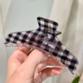 Primo piano dettagliato di un'elegante molletta per capelli a quadri neri e bianchi, trasparente. - Molla per Capelli Triangolare Minimalista G