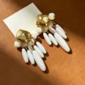 Close-up detail of vintage style gold textured square stud white teardrop tassel earrings. - White Teardrop