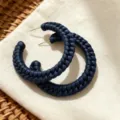 Closeup of dark blue braided leather texture hoop earrings, stylish statement jewelry detail. - Navy Blue