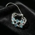 Detailed shot of a delicate silver adjustable beaded ring with translucent blue crystals. - Silver Beaded Pull Style / Blue