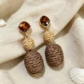 Detailed shot of retro woven raffia earrings with sparkling brown crystal and natural texture. - Coffee
