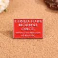 Close-up detail van een rode metalen broche met gegraveerde Engelse tekst, tasdecoratie. - De Ergste Twee Minuten