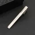 Close-up detail shot of a sleek silver metal tie clip featuring elegant linear engraved patterns. - Partial Striped Simple Style (J54)