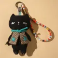 Handmade black cat plush keychain with plaid vest and colorful woven strap pendant ornament. - Black Cat