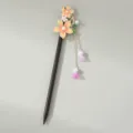Detail van de traditionele haarspeld met oranje emaille bloemen en hangende parelkwastjes. - Zwart