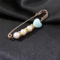 Close-up of a gold-tone safety pin brooch with white pearls, rhinestones and blue heart charm. - Light Blue Heart Style
