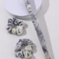 Gedetailleerd overzicht van tie-dye fluwelen haarelastiekjes en lintset, zacht en chic. - Beigegrijs