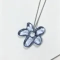 Close-up of blue translucent flower pendant necklace, elegant glass floral jewelry detail. - Blue Petals