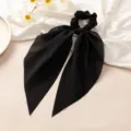 Gros plan sur l'élastique à cheveux noir élégant avec de longs rubans en tissu doux. - Noir