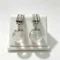 Detail view of silver C-hoop earrings with clear crystal glass sphere drops, elegant. - Transparent