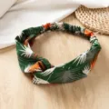 Detailopname van de brede kruisende haarband met tropische bladenprint en fijne stof. - Groen Tropisch Bloemen