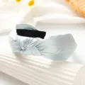 Detailed close-up view of the light blue satin knotted fabric headband accessory. - Blue
