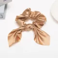 Gedetailleerde close-upopname van de elegante champagnekleurige satijnen haarscrunchie. - Champagne