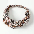 Close-up detail van de stijlvolle gedraaide haarband met abstract dierenpatroon. - Khaki