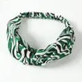 Gedetailleerde close-up van de elastische haarband met groen-zwarte abstracte print stof. - Groen
