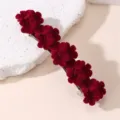 Detailopname van een donkerrode fluwelen bloem haarspeld met gedetailleerde gestructureerde bloemen. - Rood