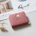 Primo piano dettagliato del portafoglio corto in pelle rosa con grazioso emblema di margherita. - colore fagiolo rosso