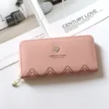 Primo piano dettagliato del portafoglio rosa lungo con cuore in metallo e chiusura zip. - Rosa chiaro