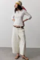 Vue détaillée de pantalon denim large et décontracté pour femme, associé à un haut blanc. - S / Blanc